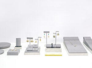 Modular jewelry display system for pop-up store, stackable risers, and velvet tray insert with campaign signage.