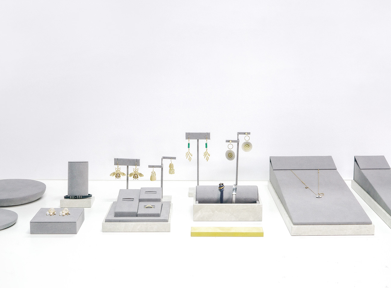 Modular jewelry display system for pop-up store, stackable risers, and velvet tray insert with campaign signage.