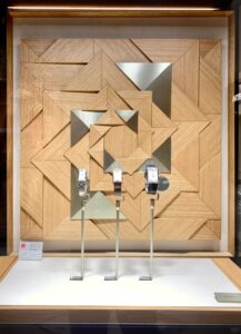 Premium retail fixture combining brushed metal, frosted acrylic, and walnut veneer