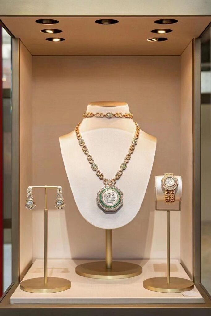 Luxury jewelry display case with a gold metal frame showcasing a necklace, earrings, and a watch on elegant metal stands, providing a sophisticated and secure presentation for high-end accessories.