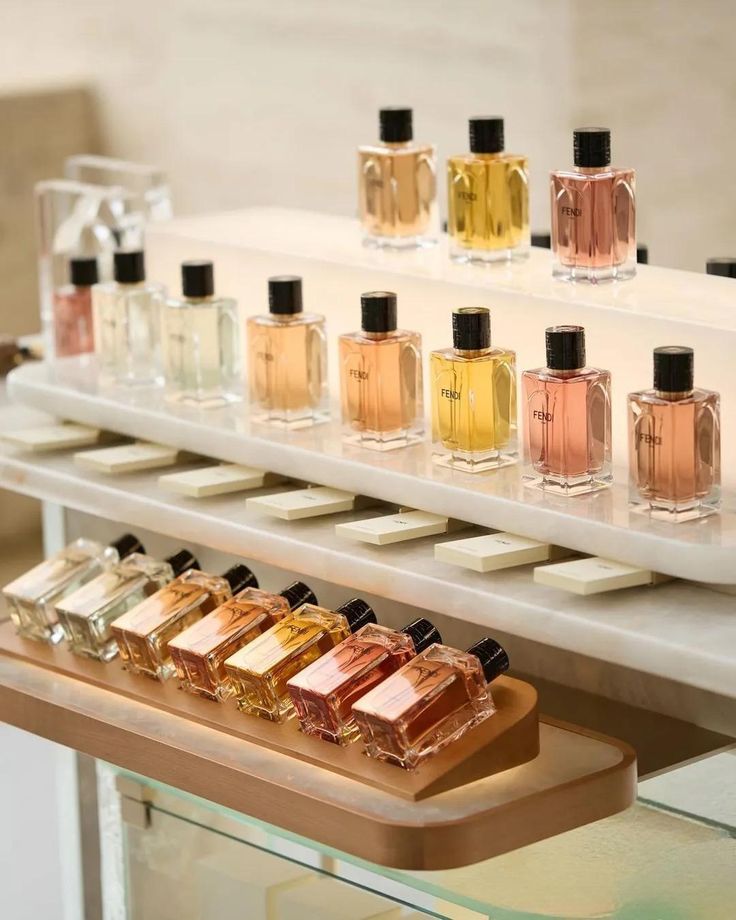 Luxury fragrance bottles displayed on illuminated faux marble shelves with refined seasonal merchandising by Samtop Display.
