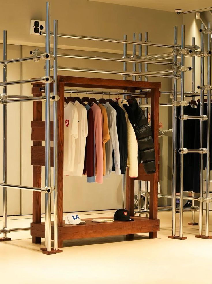 Retail display unit featuring a mix of metal and wood, showcasing clothing items in a stylish and sophisticated setting. The combination of sleek metal scaffolding and rich wooden shelves offers a modern yet warm atmosphere, ideal for high-end retail environments.