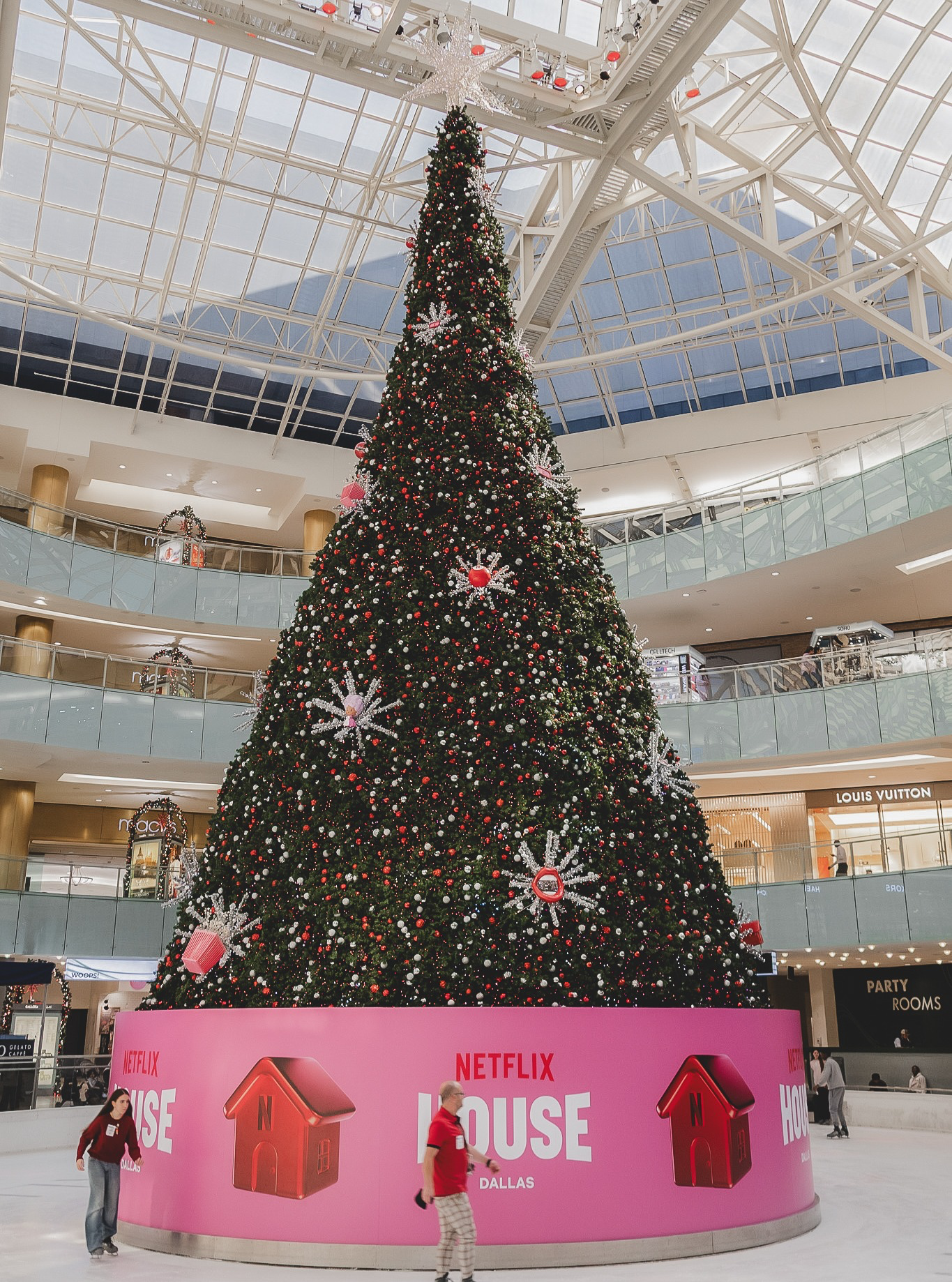 95-foot modular Christmas tree installation at Galleria Dallas for Netflix House Dallas, decorated with red and white ornaments and a Netflix House branded pink base