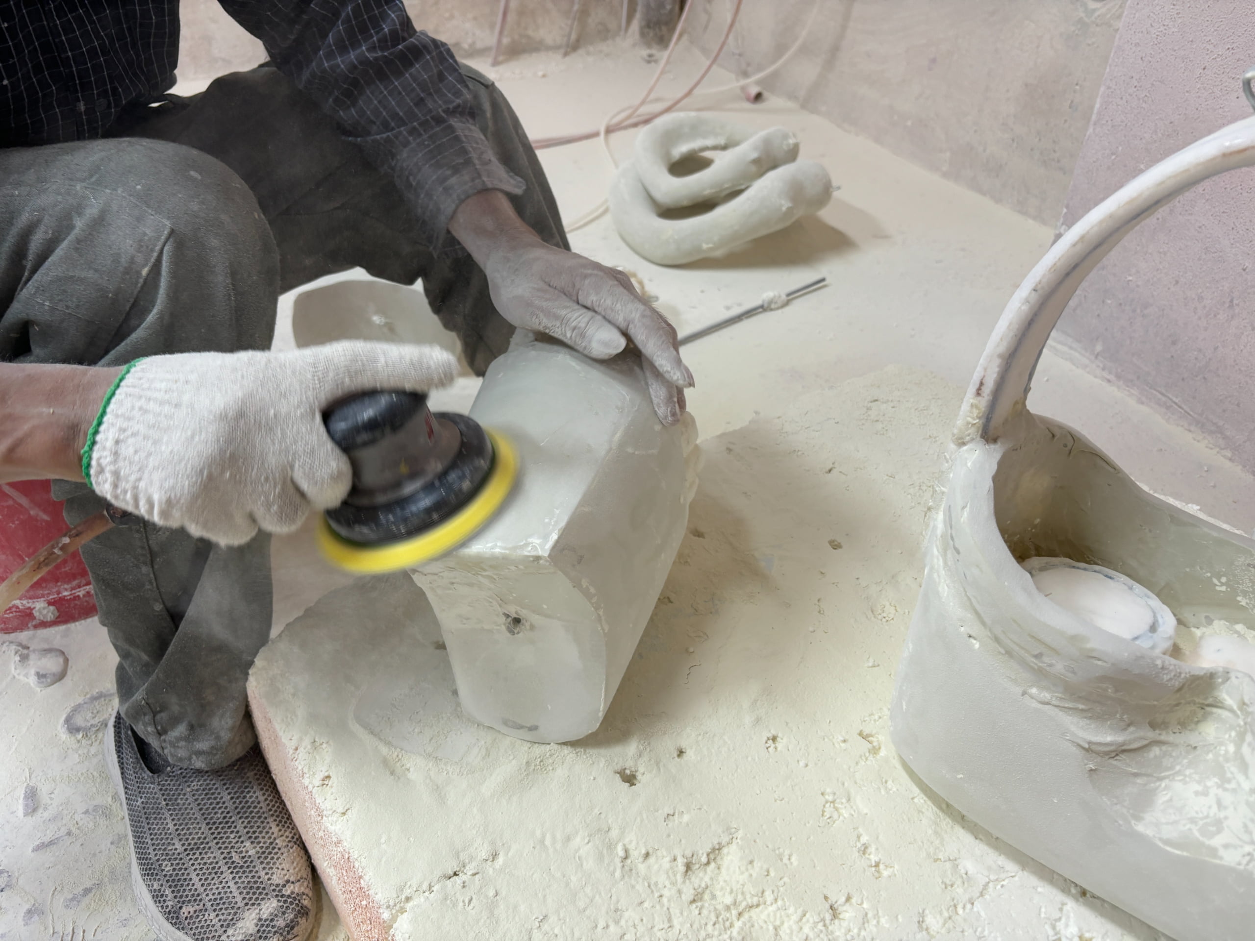 Factory worker sanding a resin prop surface to remove mold lines before primer application, part of Samtop's five-stage custom prop production process