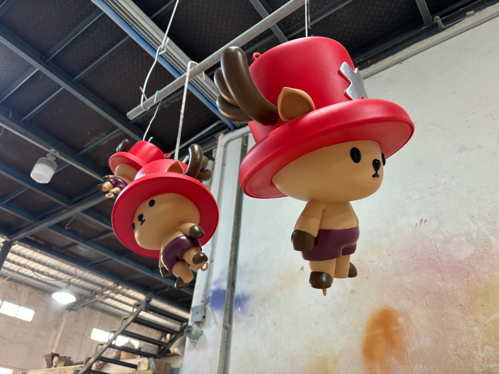 High-detail resin character ornaments suspended in the workshop during finishing for a large holiday retail installation.