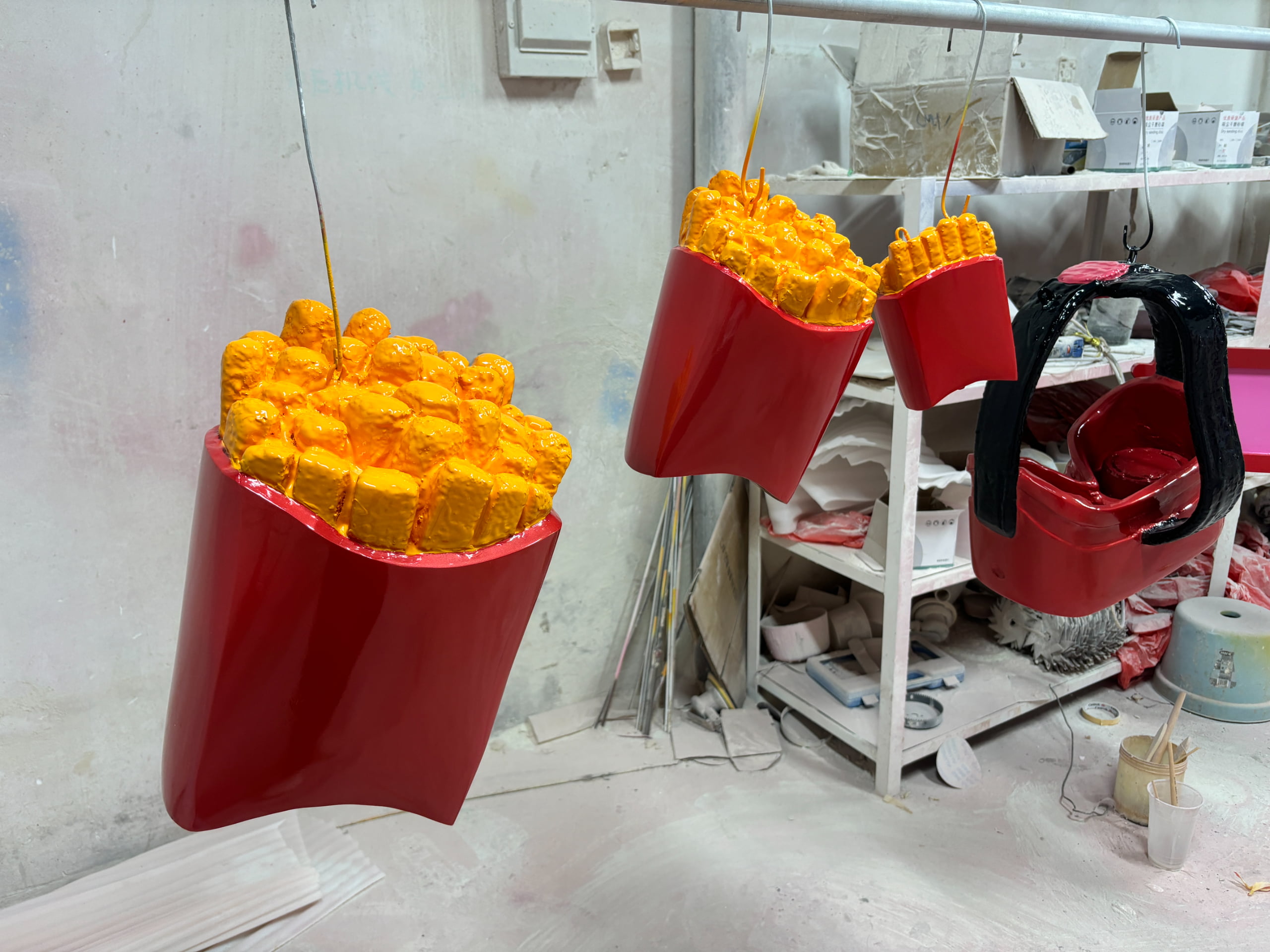 Oversized French fries props suspended for weight stability testing and hanging safety inspection before mall installation.