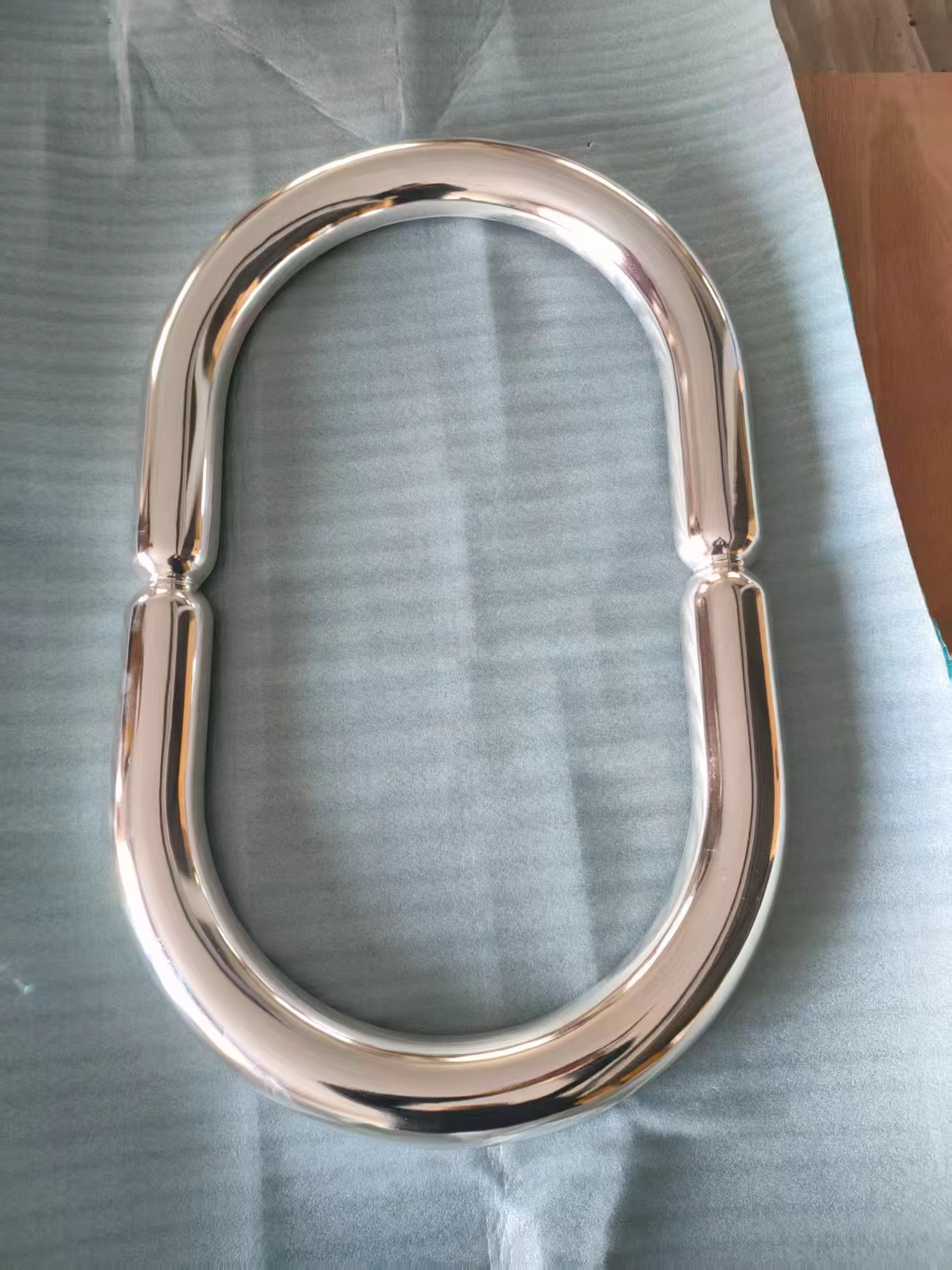 A polished chrome effect oval balloon frame prop carved from PU foam resting on protective wrap showing smooth curves and mirror like reflection.