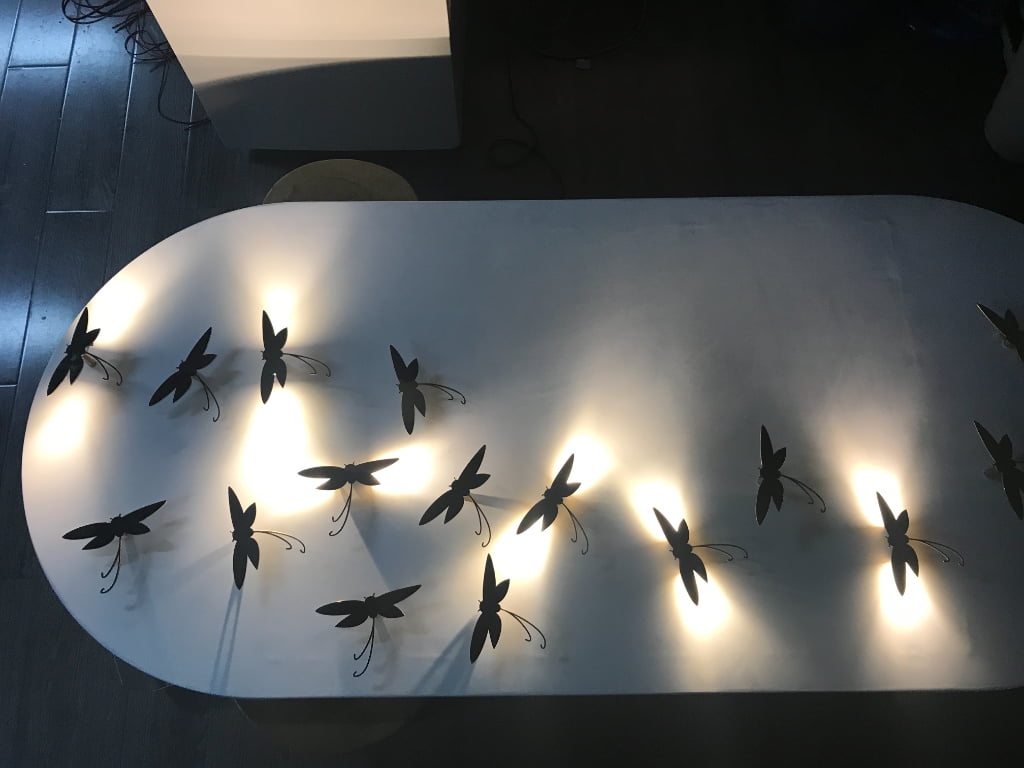 Multiple illuminated dragonfly display props creating a soft halo lighting effect