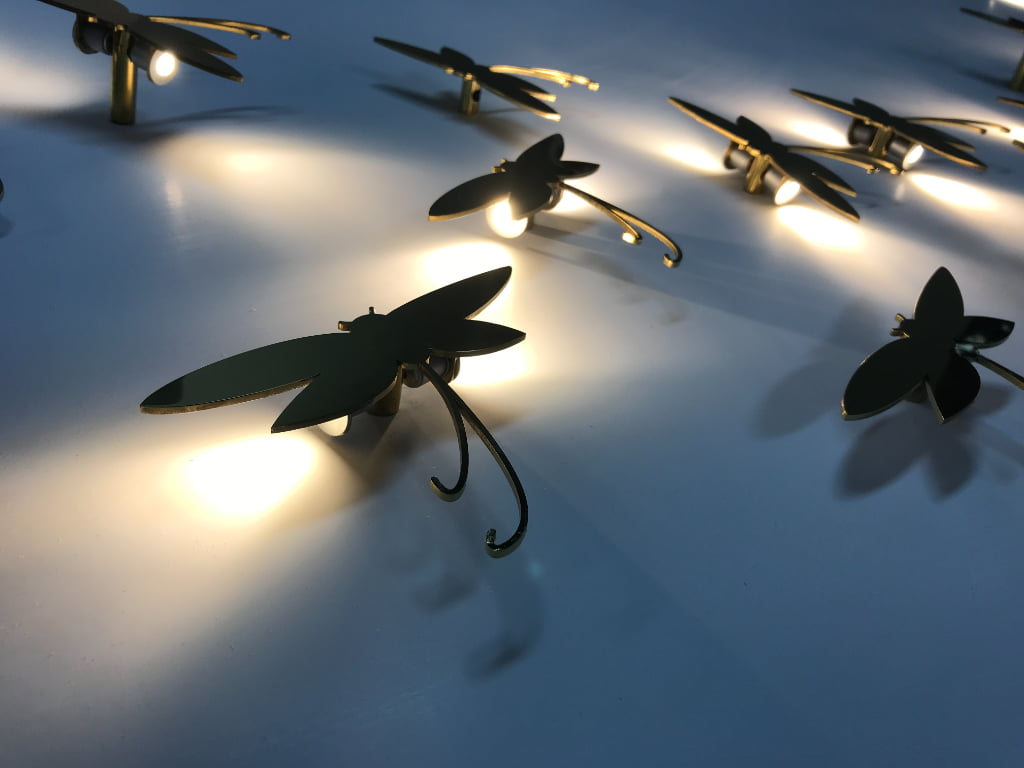 Custom illuminated dragonfly display props creating a warm lighting effect for luxury retail window displays