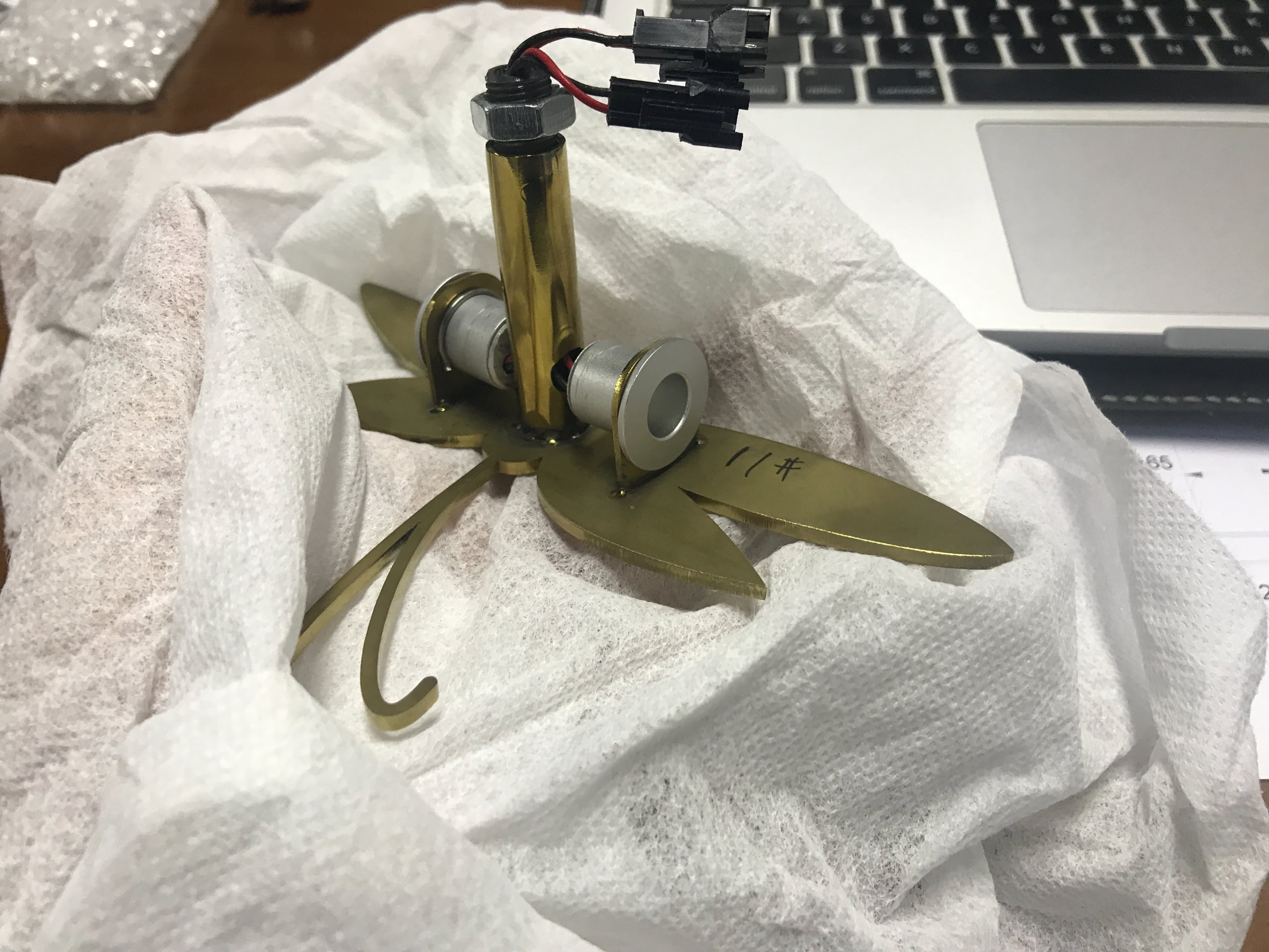 Hidden wiring routed through a hollow brass support tube inside a custom lighted display prop
