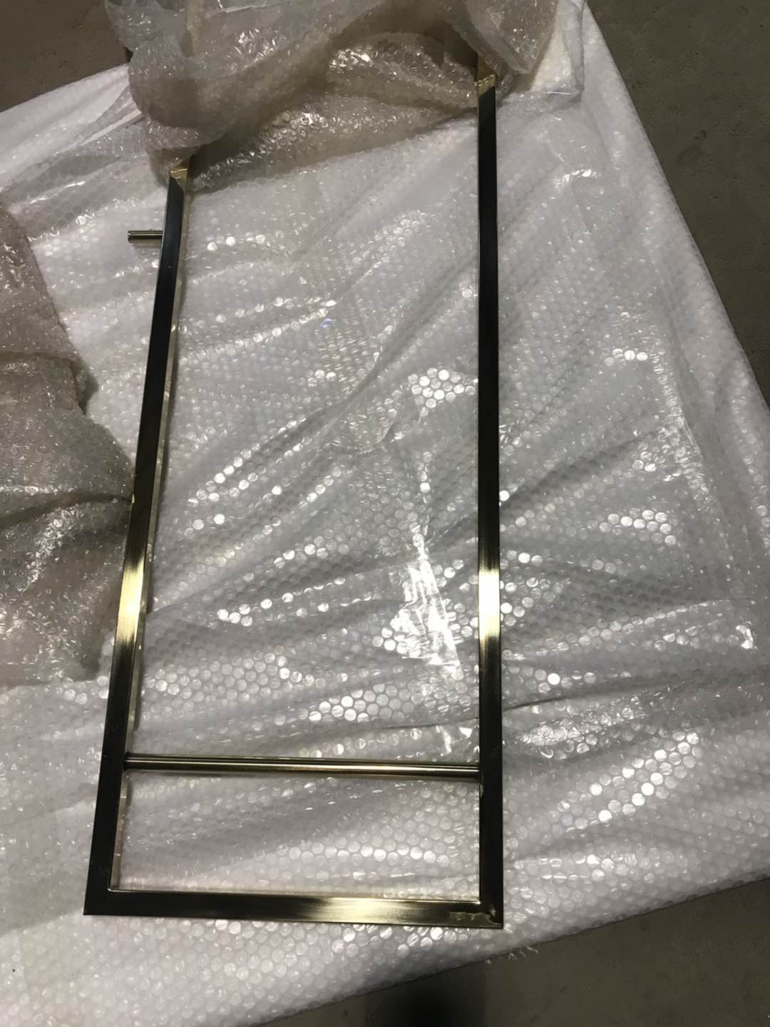 Gold PVD finish on a custom metal display stand frame showing the reflective surface and finished joints