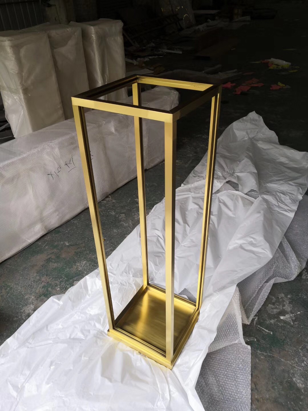 Custom metal display stand with a gold finish for luxury retail merchandising