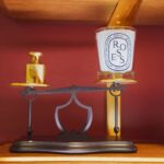 Custom perfume display stand with brass platform and black metal balance structure