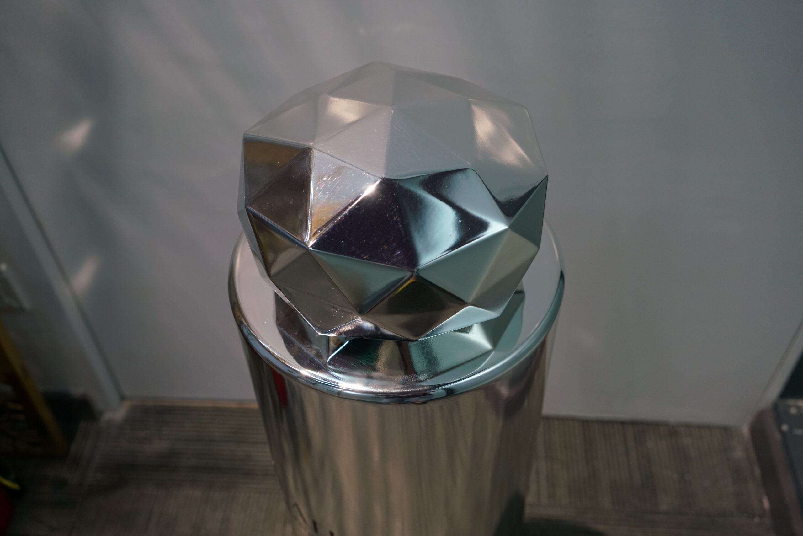 Close-up of the geometric perfume bottle cap showing multiple reflective facets and edges
