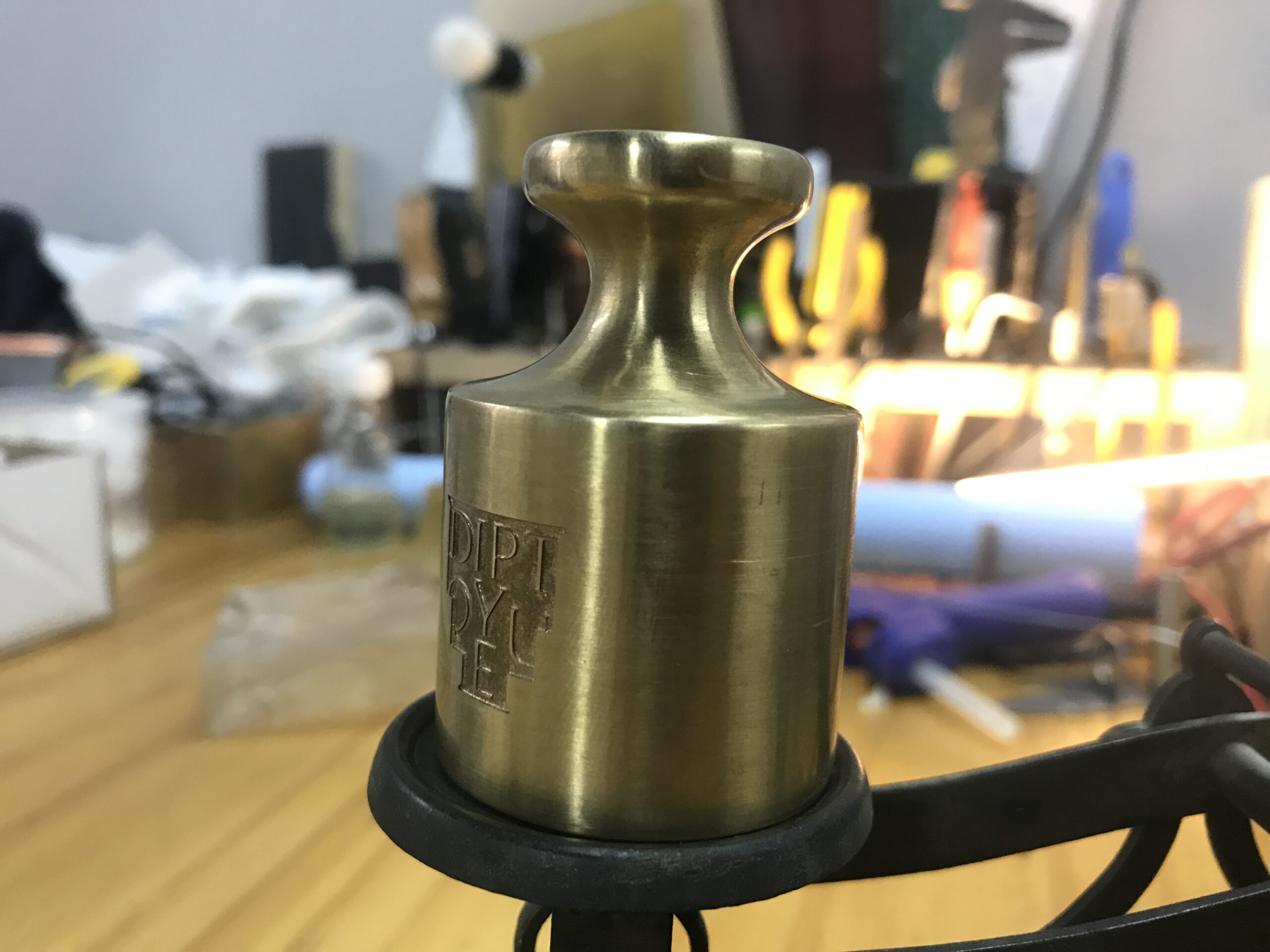 Close-up of a machined brass weight with brushed finish and engraved branding