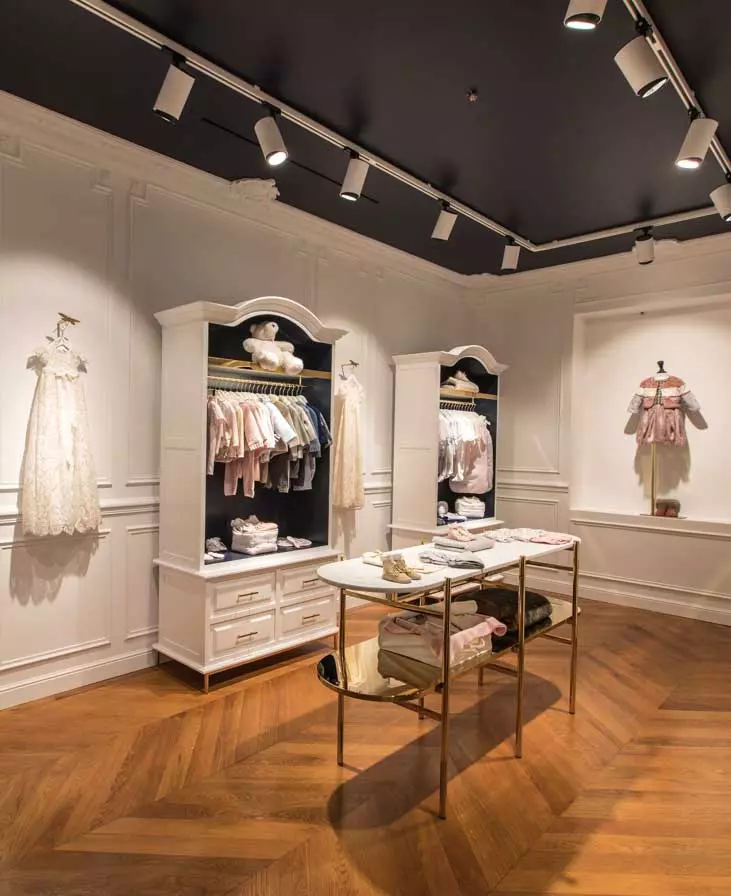 Custom metal display stands and gold-finished retail fixtures in a luxury fashion store