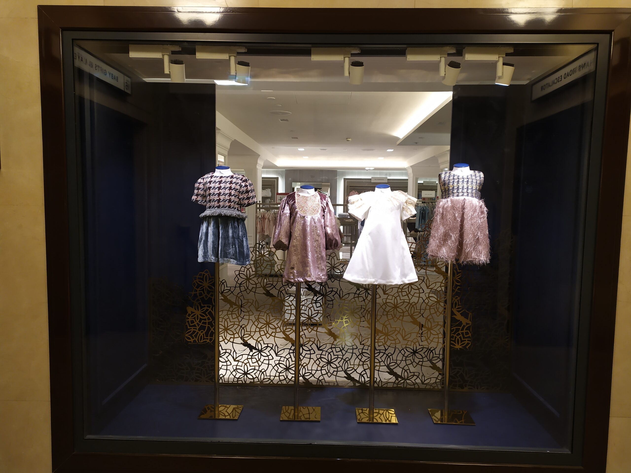 Custom metal display stands used in a luxury retail window with gold decorative metalwork