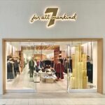 Christmas tree prop with illuminated gold chain columns installed at a fashion retail storefront.