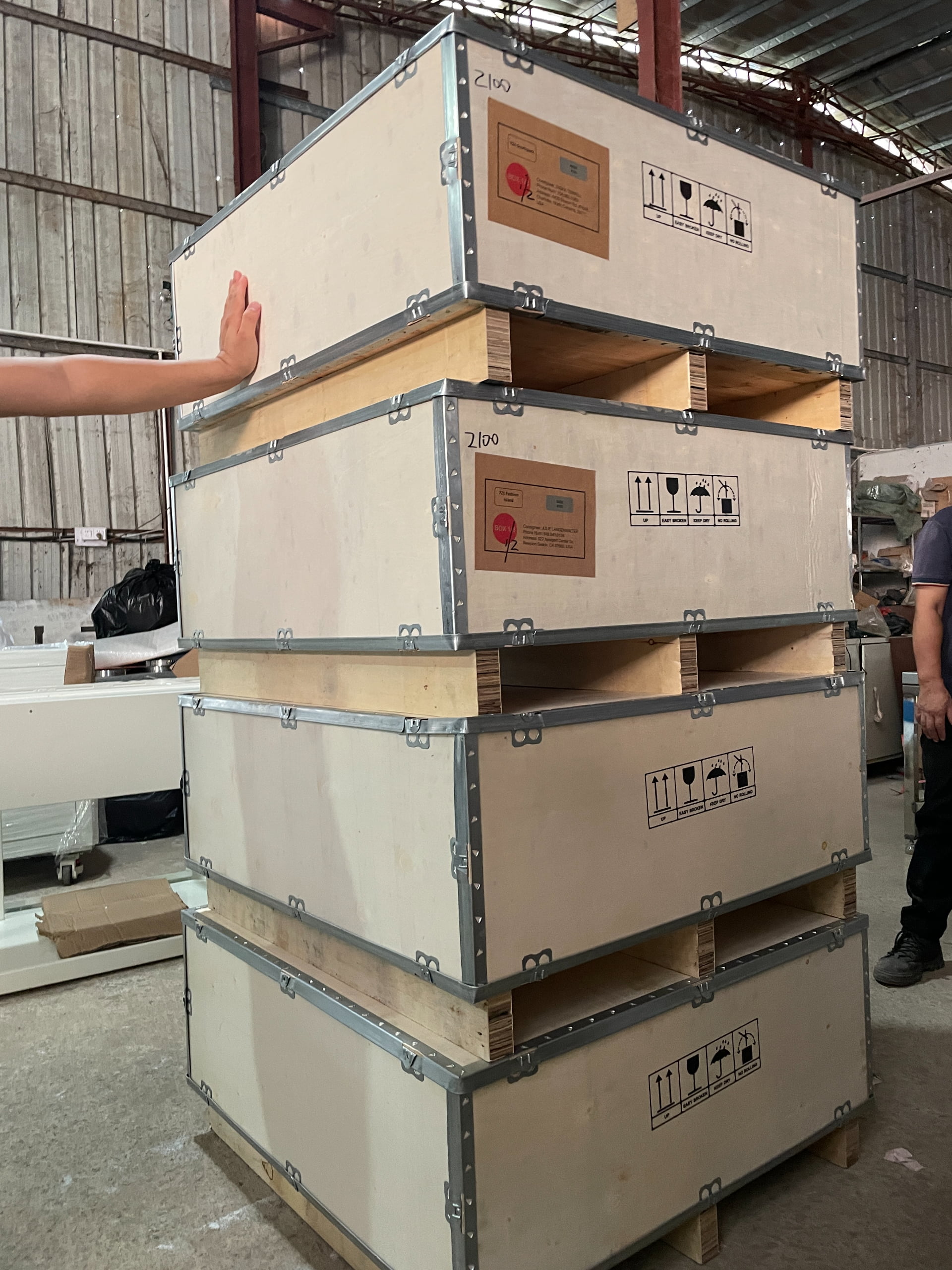 Stacked reinforced wooden crates prepared to protect metal, lighting, and decorative components during international shipping.