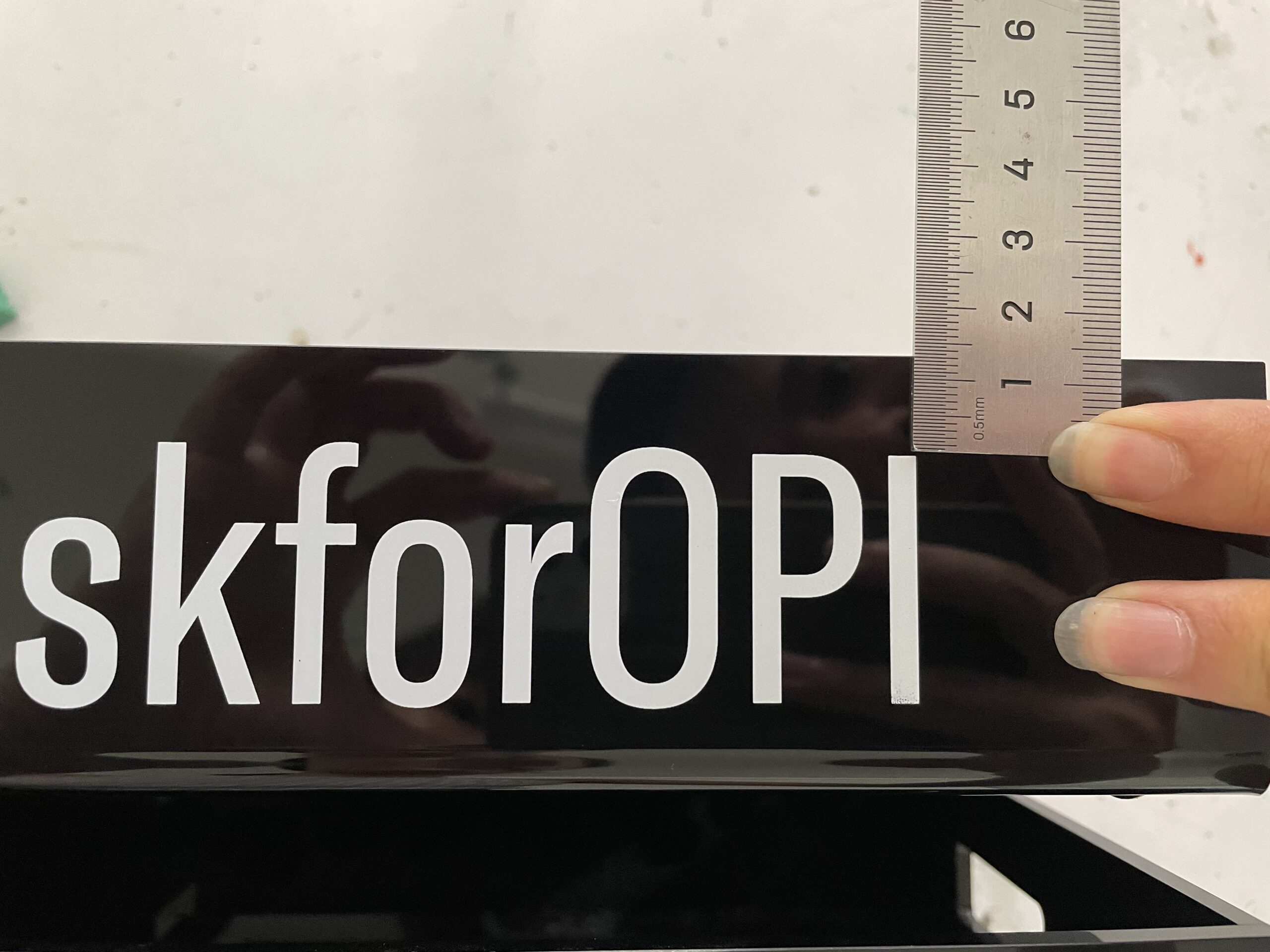 Measuring the position of white OPI branding on a glossy black acrylic panel
