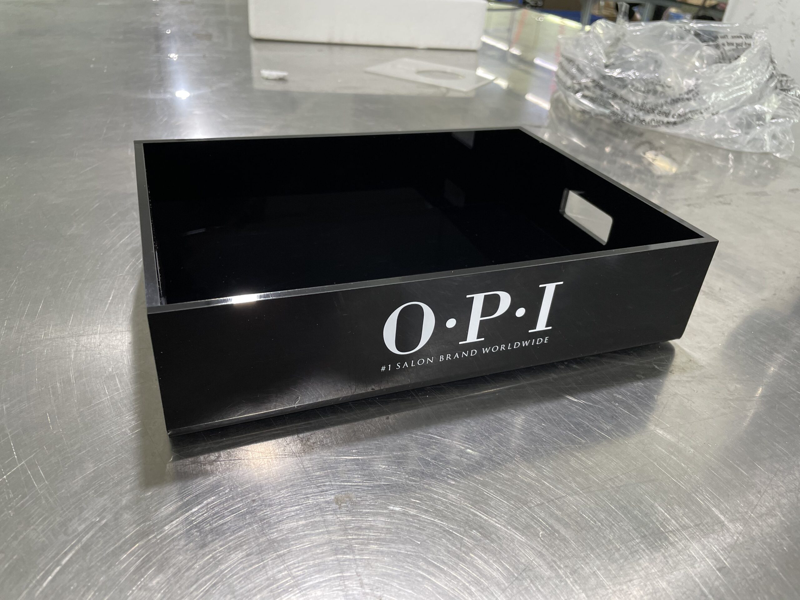 Custom glossy black acrylic display tray with white OPI branding for beauty retail merchandising