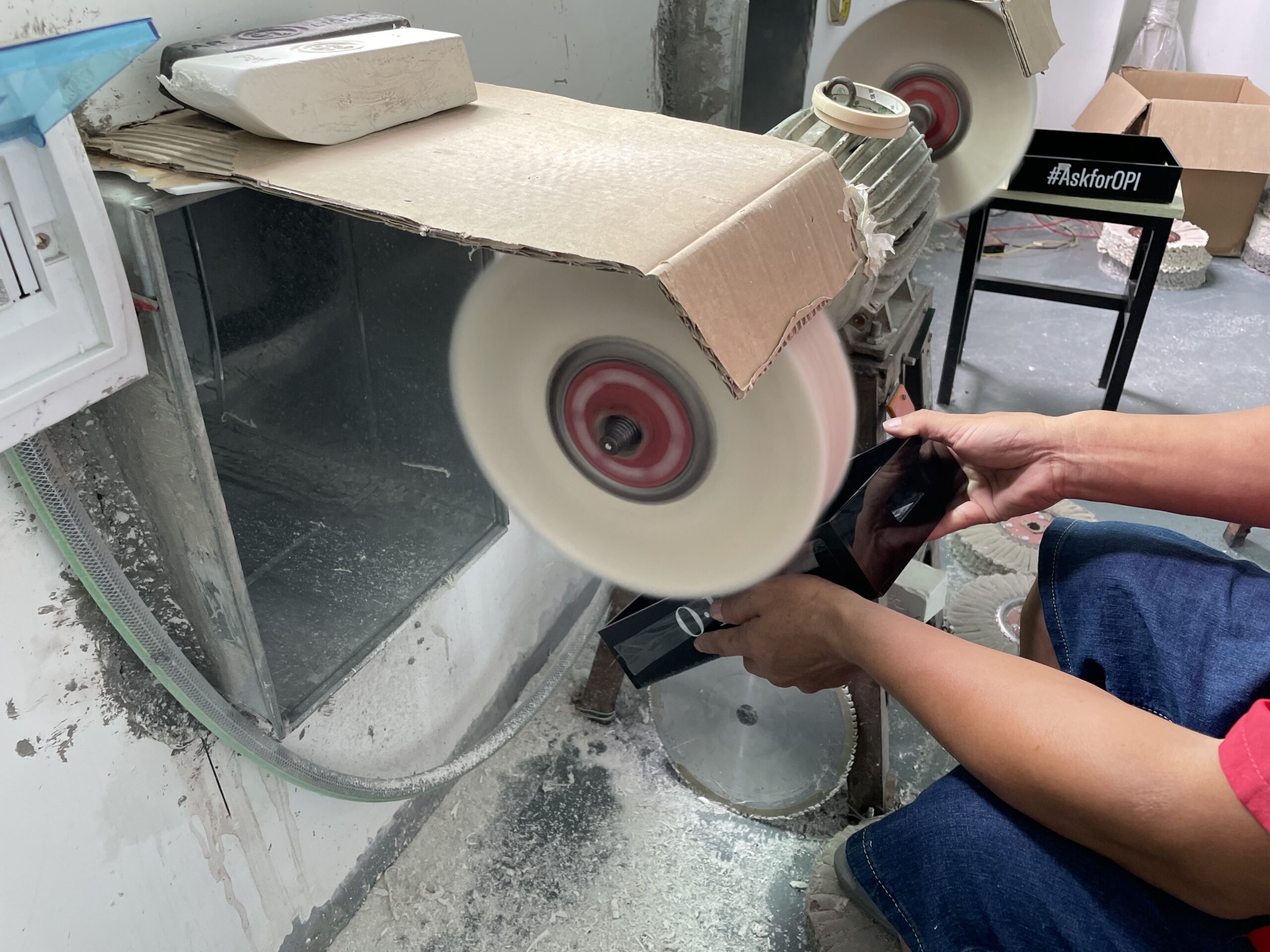 Worker polishing exposed edges on a glossy black acrylic component during production