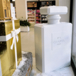 Oversized perfume bottle retail displays with geometric shapes, white and metallic gold finishes, illustrating different retail display design considerations.