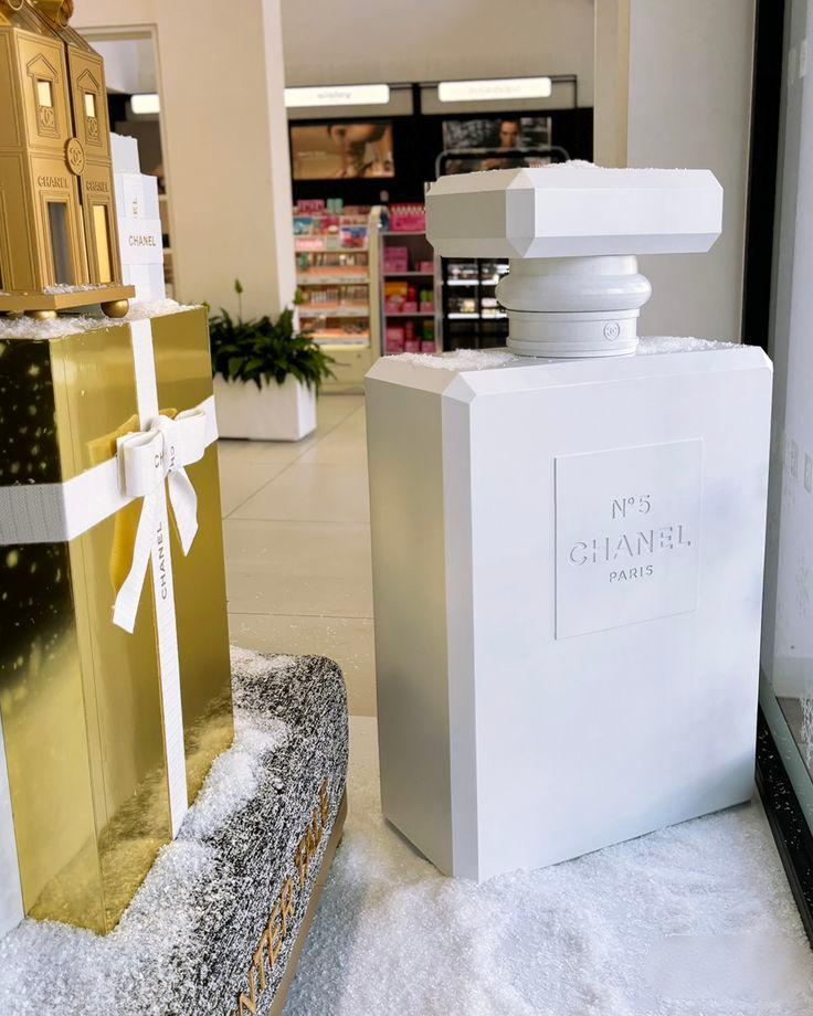 Oversized perfume bottle retail displays with geometric shapes, white and metallic gold finishes, illustrating different retail display design considerations.